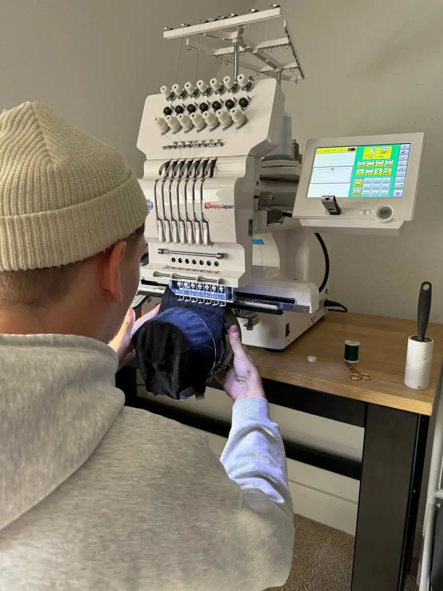Eine Cap wird in unserer Hamburger Werkstatt auf der Mehrnadel-Stickmaschine mit einem Firmenlogo bestickt
